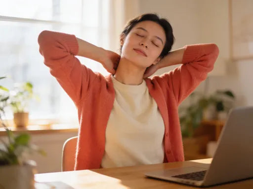 Person gently stretching neck at a home desk, warm natural light